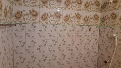 a bathroom with flowers on the wall of a shower at KANTHI GUEST INN in Trincomalee