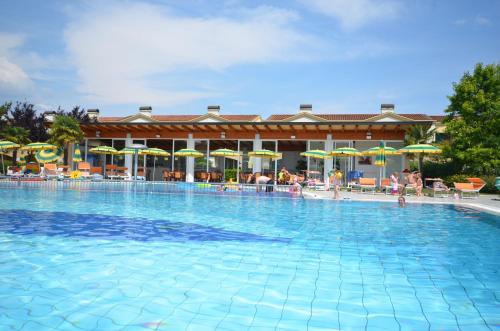 a large swimming pool with chairs and umbrellas at Villaggio Marco Polo in Bibione