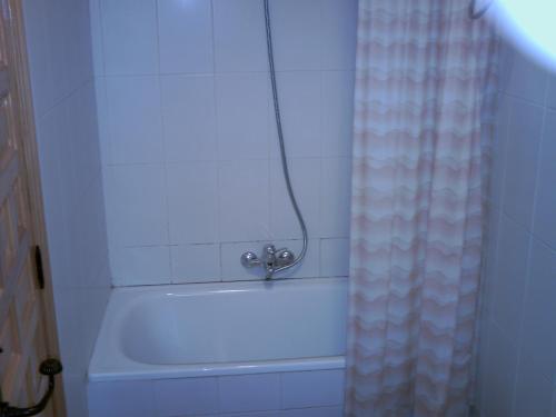 El baño incluye bañera blanca con cortina de ducha. en Casa Lopez en San Martín del Castañar