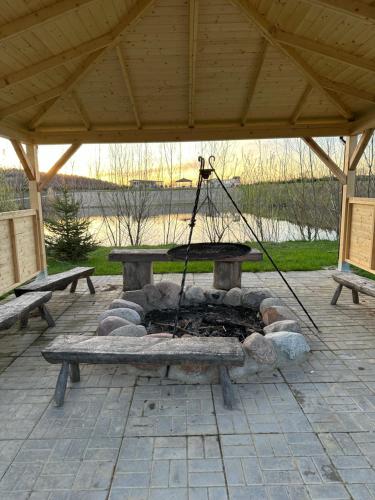 a fire pit in a pavilion with two benches at Domki Nad Sanem Bachórzec 6a in Dubiecko