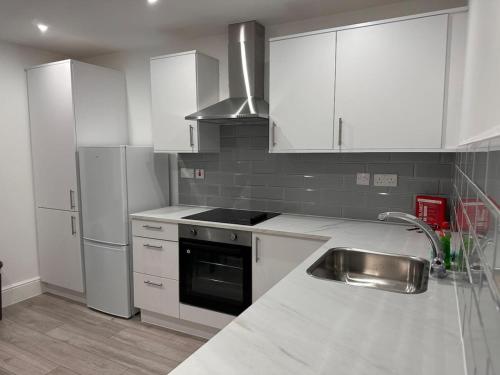 a kitchen with white cabinets and a stove and a sink at Modern Central London Room Zone1 in London