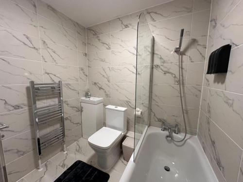 a white bathroom with a toilet and a bath tub at London Vauxhall - Victoria room in London