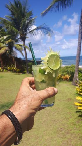 a hand holding a drink with a slice of lime at Casa Del Mar in Marau