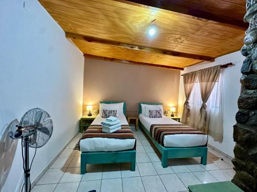 a room with two beds and a fan at Hostal Qachi Chentura in San Pedro de Atacama