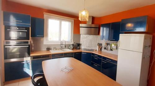 uma cozinha com armários azuis e uma mesa de madeira em Charmante maison néo-bretonne em Plumaudan