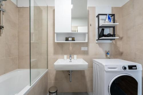 ein Badezimmer mit einem Waschbecken und einer Waschmaschine in der Unterkunft HM • Urban 1BR Retreat, Easy City Link in Wien