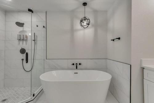 a white bathroom with a tub and a shower at Gorgeous Sunny Home for Big Groups w Private Pool in Garland