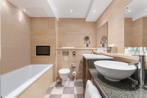a bathroom with a tub and a sink and a toilet at Spa Hotel at Ribby Hall Village in Wrea Green