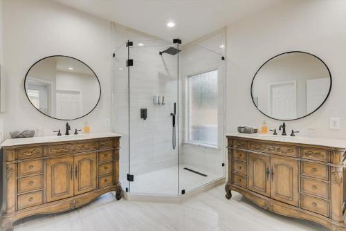 uma casa de banho com 2 lavatórios e um chuveiro com 2 espelhos em Spacious and Luxury Home w Cinema Room and Pool em Grand Prairie