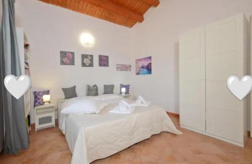 a white bedroom with a bed and two hearts on the wall at Il Rifugio della Quiete in Scicli
