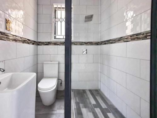 Kumwitu Luxury Apartments في لوساكا: حمام ابيض مع مرحاض ومغسلة