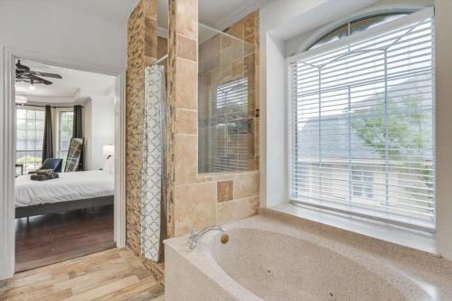 a bathroom with a tub and a large window at Creekside Charm w Pool Backyard Oasis Patio in Plano