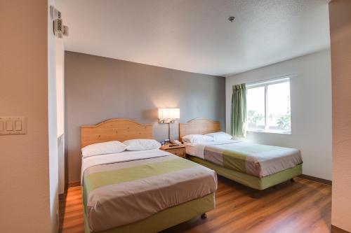 a hotel room with two beds and a window at Studio 6-Brownsville, TX in Brownsville