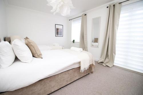 a white bedroom with a large bed and a window at 5 bedroom sleeps 10 | City Centre Newport in Newport