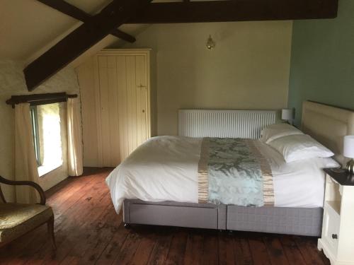 a bedroom with a bed with white sheets and a window at The Coach House New Quay in Cross Inn