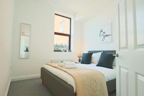 a bedroom with a bed with blue pillows and a window at Lovely Salisbury 1 bedroom flat in Bristol
