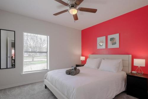 a bedroom with a white bed with a red wall at Vibrant Spacious Home w Private Pool and Jacuzzi in Richardson