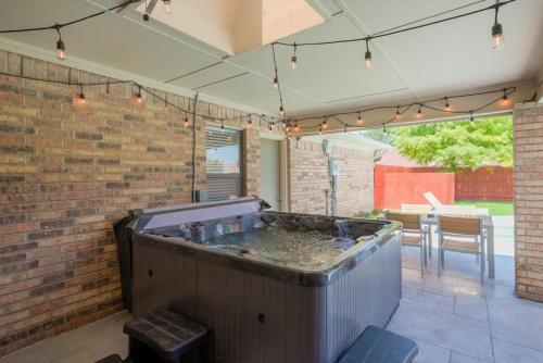 a hot tub on a patio with a brick wall at Vibrant Spacious Home w Private Pool and Jacuzzi in Richardson