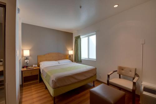 a bedroom with a bed and a chair and a window at Studio 6-Brownsville, TX in Brownsville