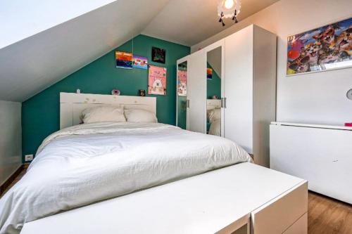 um quarto com uma cama branca e paredes verdes em Maison spacieuse de 100m2 avec 3 chambres et jardin à 10 min à pied de la gare de meaux, 20 min de Disney et 30 min de paris em Villenoy