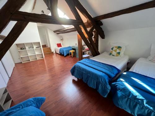 a attic bedroom with two beds and a table at Le Moulin de Corneil in Mézilles