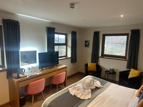 a bedroom with a bed and a desk with a television at Afan Lodge in Port Talbot