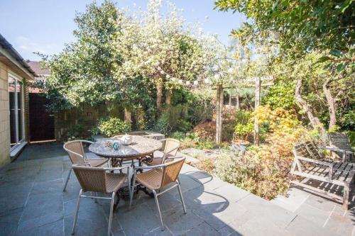 a patio with a table and chairs in a garden at ※ Relaxing Home- Parking & Gorgeous Gardens (TSG)※ in Bath
