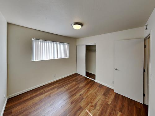 an empty living room with a window and wooden floors at San Jose Apartment in San Jose