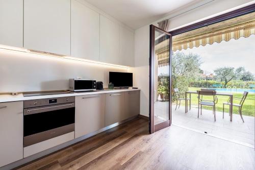 a kitchen with white cabinets and a sliding glass door at Appartamento Colibri in San Felice del Benaco