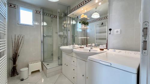 ein weißes Bad mit einem Waschbecken und einer Dusche in der Unterkunft Pointe de Sel, appartement face au port du Crotoy in Le Crotoy