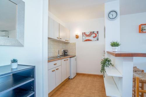 エンプリアブラバにあるBasic Comfort Apartment Gran Reserva 0073の白いキャビネットと壁掛け時計付きのキッチン