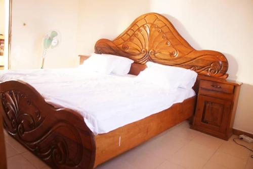 a large bed with a wooden headboard and a night stand at Moyite Gandiol in Ndiébène