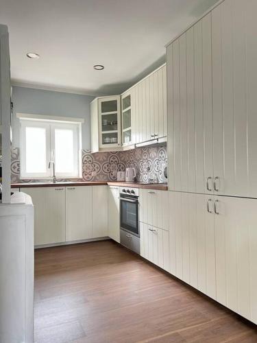 a kitchen with white cabinets and a wooden floor at Casa Santa Rita in Alcobaça