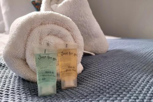 two bottles of just five products on a bed with a towel at No.62 Fivedom - Luxury apartment in Southampton