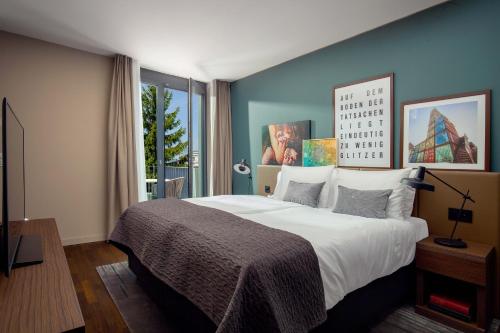 ein Schlafzimmer mit einem großen Bett und einem großen Fenster in der Unterkunft Acasa Suites in Zürich