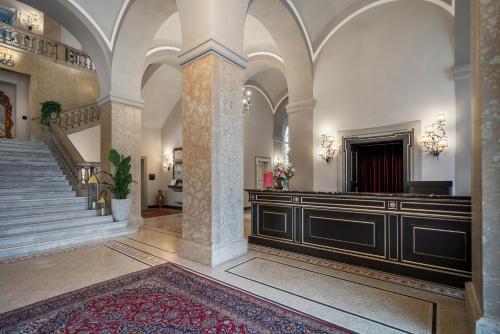 a large lobby with a staircase and a building at Grand Hotel di Parma | UNA Esperienze in Parma