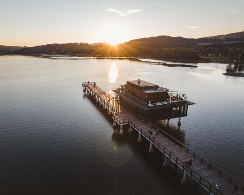 a dock on a body of water with the sun setting at MOLO LIPNO RESIDENCE in Lipno nad Vltavou
