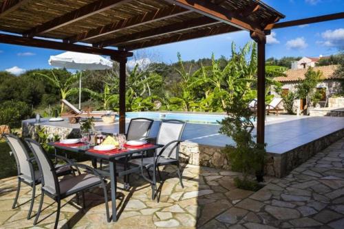 a patio with a table and chairs next to a pool at 1841 Petrino Villa in Fiskardho