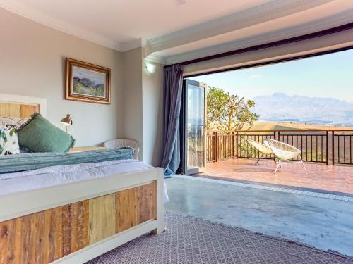 ein Schlafzimmer mit Bett und Balkon mit Aussicht in der Unterkunft Shiloh Cottage in Champagne Valley