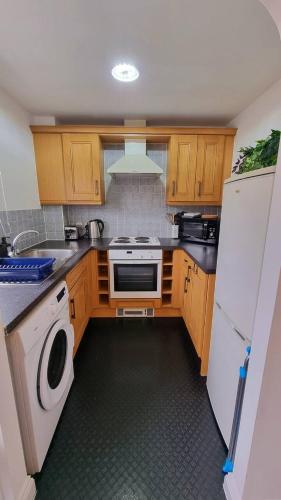 a kitchen with wooden cabinets and a washer and dryer at No 62 A Smart Stay in Southampton - GREAT PRICE and Stylish 2-Bed - Free Parking in Southampton
