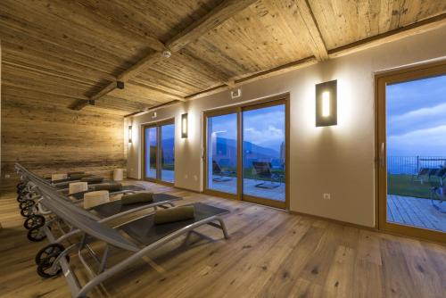 a room with a group of chairs and large windows at Panoramahotel Huberhof in Maranza