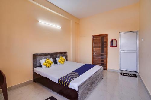een slaapkamer met een bed met gele en blauwe kussens bij SPOT ON Hotel Pragya 5 in Raipur