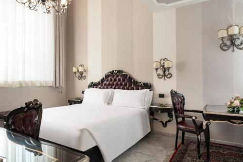 a bedroom with a large white bed and a desk at Grand Hotel di Parma | UNA Esperienze in Parma