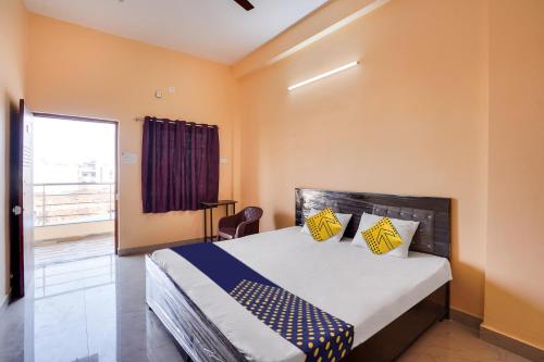 a bedroom with a bed with yellow walls and a window at SPOT ON Hotel Pragya 5 in Raipur
