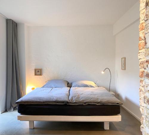łóżko w sypialni z białą ścianą w obiekcie Zehuus Gartenstudio mit Terrasse w Kolonii