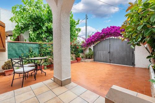 une terrasse avec une table, des chaises et des fleurs violettes dans l'établissement Preciosa casa al lado del mar, à Creixell