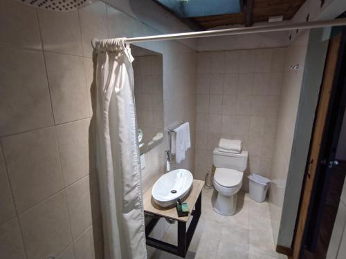 a bathroom with a toilet and a shower curtain at Posada Cafe La Huerta in Guasca