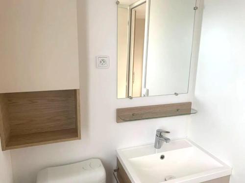 une salle de bain avec un lavabo et un miroir et des toilettes dans l'établissement Bungalow confortable à Sérignan avec piscine partagée, à Sérignan
