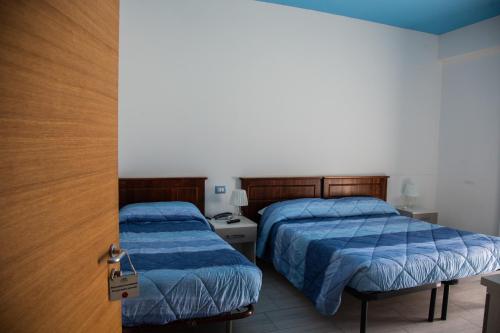 a bedroom with two beds and a door with a key at Hotel Pina Ristorante in Isola del Gran Sasso dʼItalia