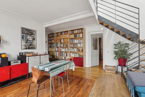 un salon avec une table et des chaises et un escalier dans l'établissement L'Atypique - Charmant Duplex au coeur du 20eme, à Paris